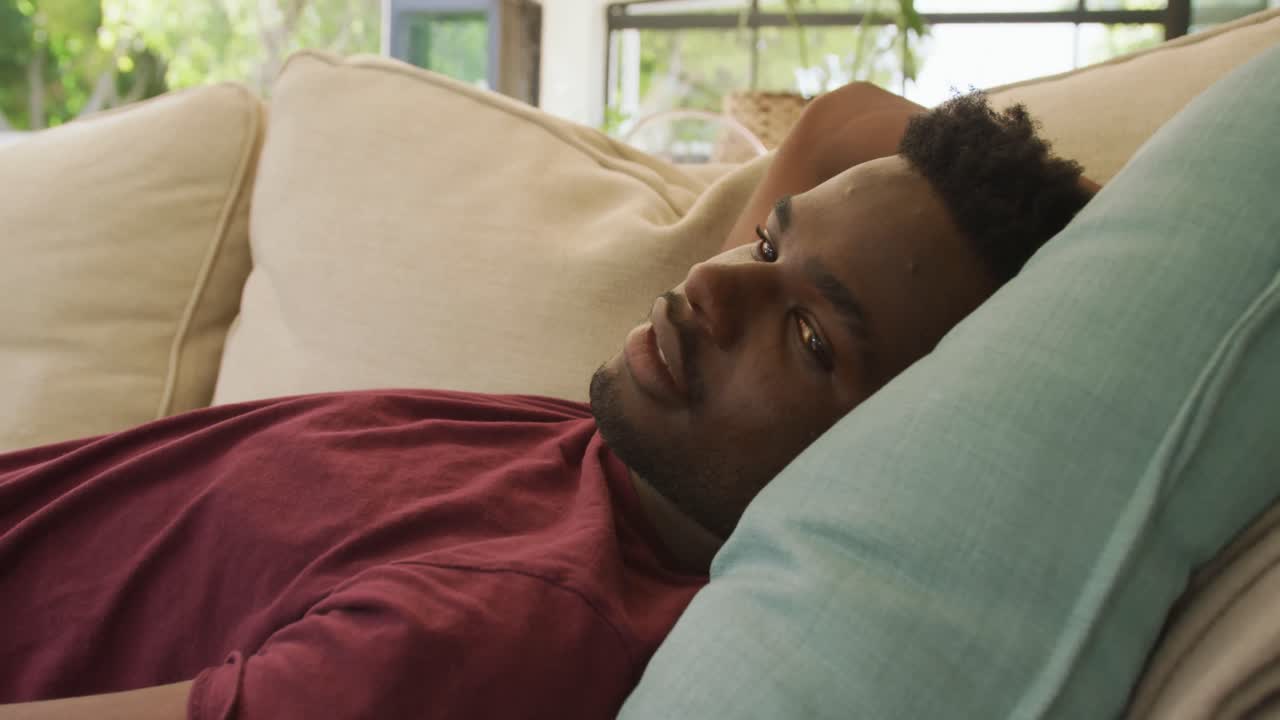 Video af afslappet afroamerikansk mand, der ligger på sofaen.