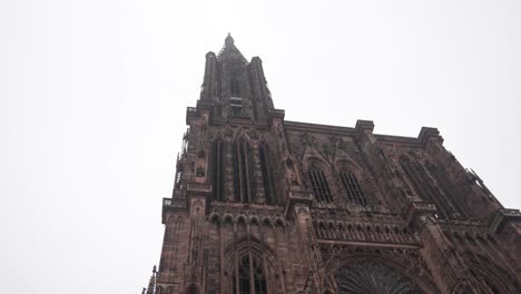 view onto the strasbourg cathedral against a cloudy sky backdrop, the intricately carved facade beckons, adorned with an array of sculptures depicting scenes from the bible and medieval life