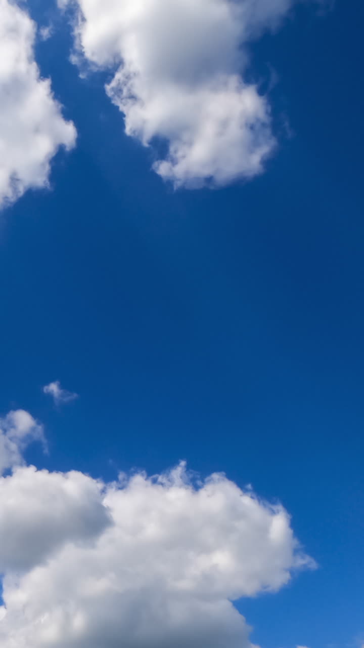White light soft clouds flying in the sky. Sunny day background. Low angle view. Timelapse. Vertical video