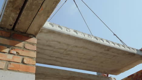 una grúa instala un panel de piso en un edificio de varios pisos una vista inferior