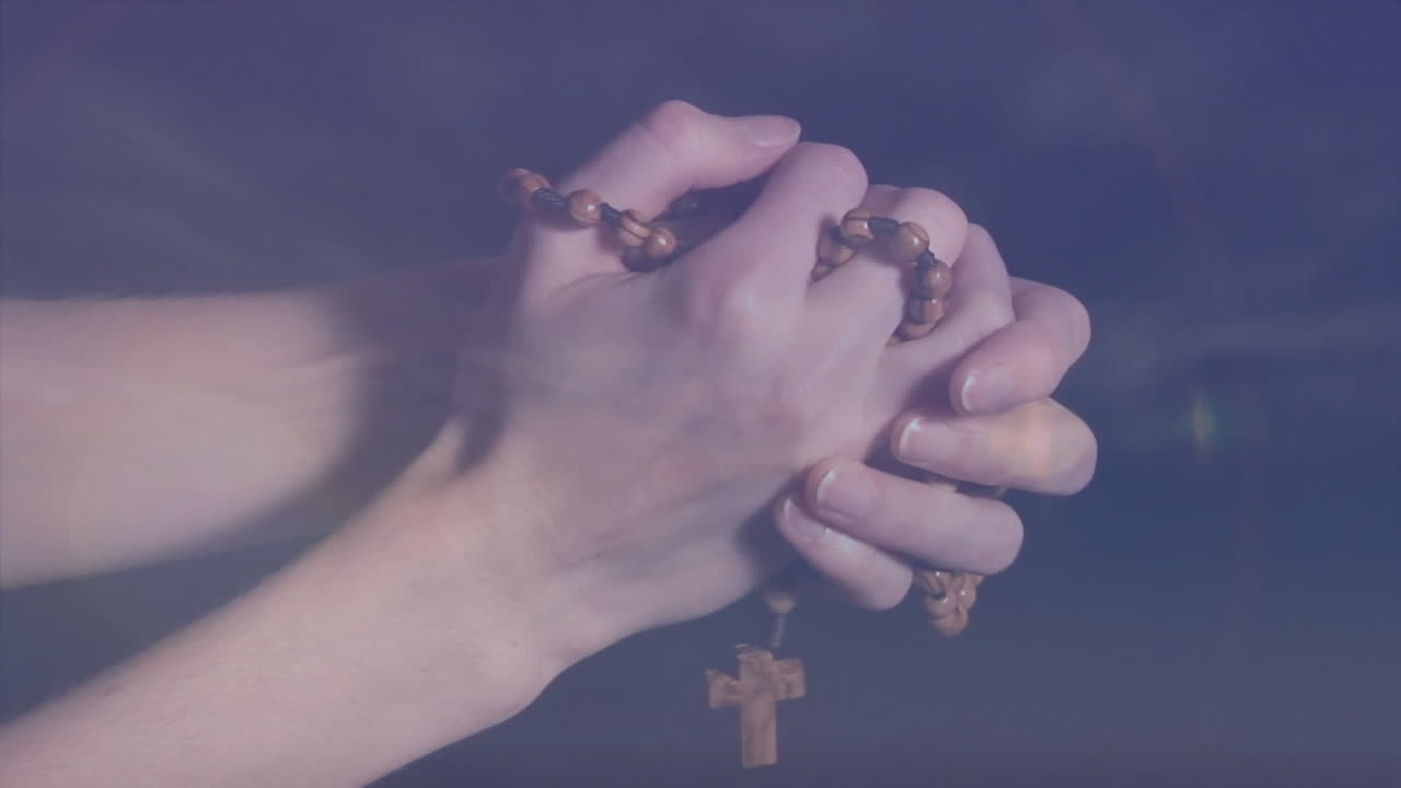 Holding rosary beads with wooden cross, hands symbolizing prayer and faith