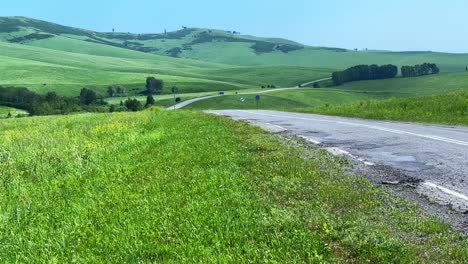 breathtaking scenic view of a serene green landscape with rolling hills and a winding road under a clear blue sky in midday light