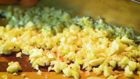 garlic is being chopped with fast knife motion, on a wooden cutting board