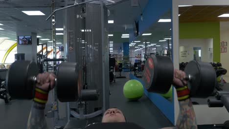 man performing bench press exercise in gym