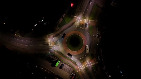aerial top down of roundabout lighting at night. traffic scene in american town. rising circling shot. busy streets in city.