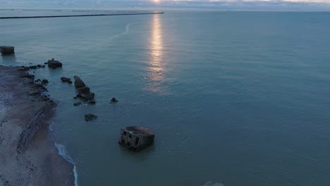 Wunderschöne-Luftaufnahme-Der-Festungsruinen-Der-Karosta-Betonküste,-Lebendiger,-Kontrastreicher-Sonnenuntergang-über-Der-Ruhigen-Ostsee,-Winterabend,-Breite-Drohnenaufnahme,-Die-Sich-Vorwärts-Bewegt,-Nach-Oben-Geneigt