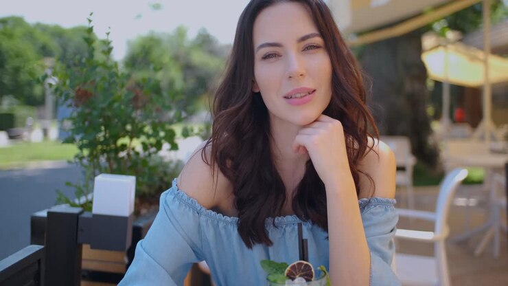 hermosa mujer sentada en un restaurante al aire libre y bebiendo mojito en un día caluroso de verano