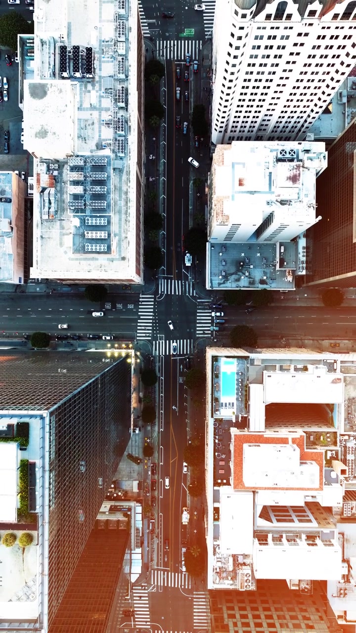 Vista aérea del centro de Los Ángeles. Rascacielos rodean calles e intersecciones concurridas. El tráfico se mueve por el centro urbano durante la hora pico. Los edificios definen el área metropolitana.