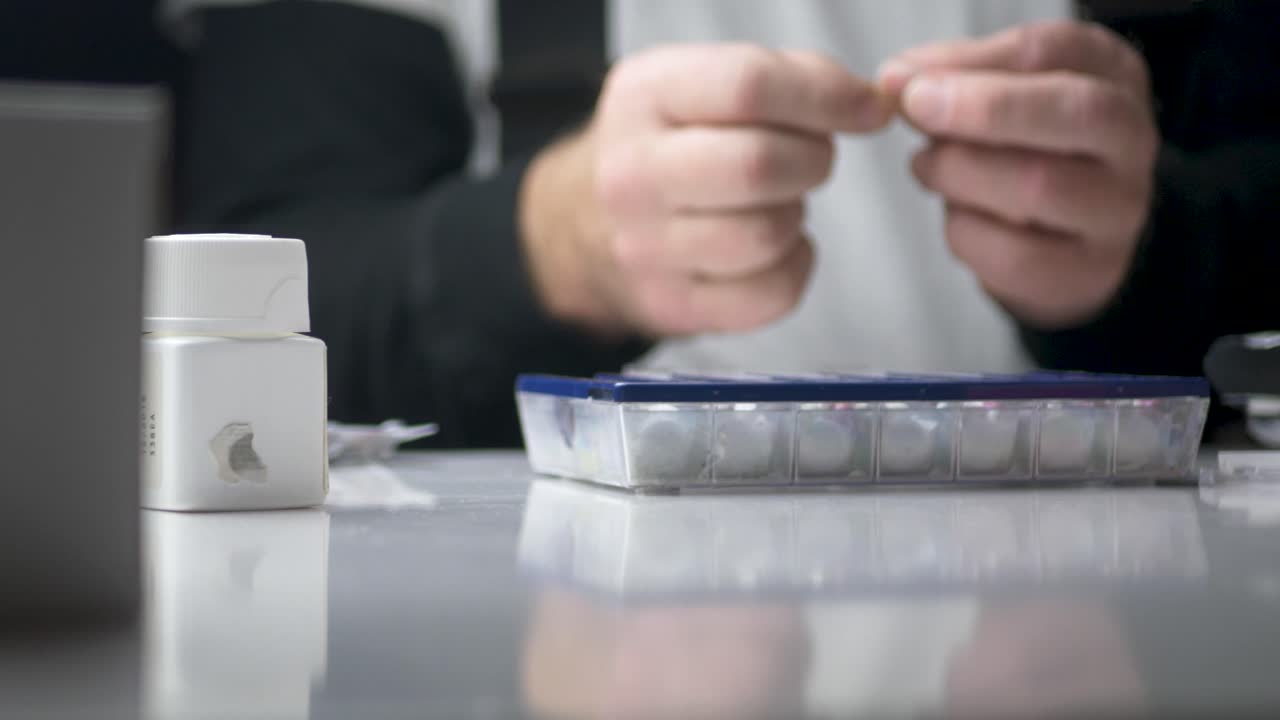 Man sorting pills into a medicine organizer dispenser - Slide close up shot