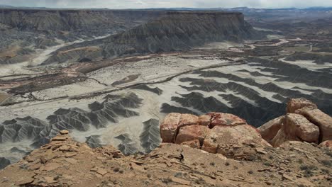 Vista-Aérea-De-Una-Persona-Femenina-Caminando-Sobre-El-Acantilado-Sobre-El-Profundo-Cañón-Del-Desierto-Gris,-Utah,-EE.UU.