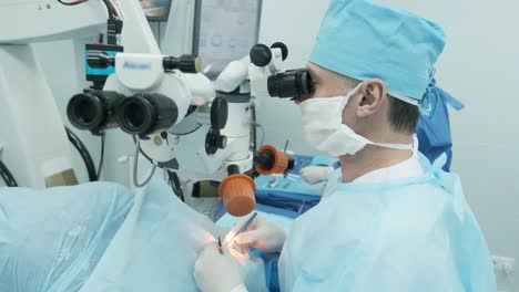 surgeon looking into the microscope at the eye of female patient at the operating room. doctor using microscope during eye surgery process, treatment of cataract and diopter correction.