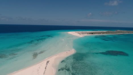 Couple-walking-alone-on-flooded-sandbank,-tropical-aerial-landscape-with-beautiful-clear-water