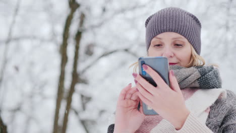 Young-Woman-Uses-Smartphone-In-Snow-Park