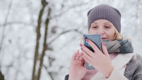 young woman uses smartphone in snow park