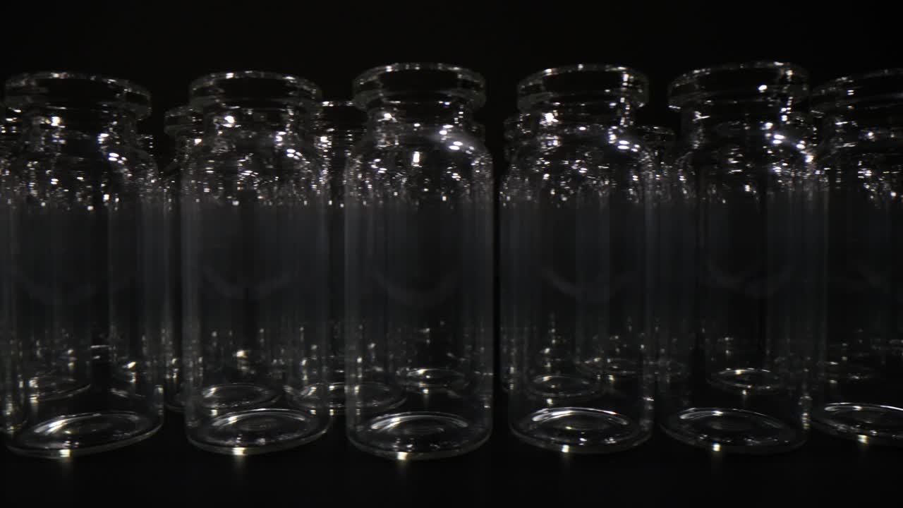 Rows of Empty Clear Glass Vials on a Dark Background