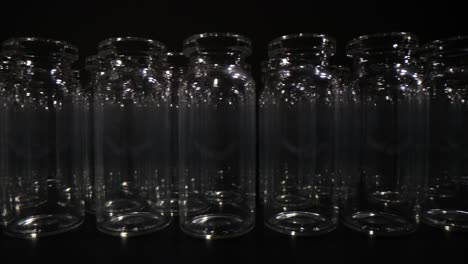 rows of empty clear glass vials on a dark background