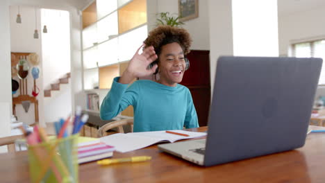 african american boy wearing headphones, using laptop for online class, slow motion