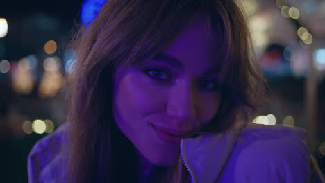 mujer feliz sonriendo cámara por la noche parque iluminado con luces festivas de primer plano