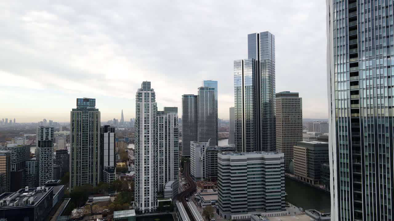 toma aérea cinematográfica de edificios de rascacielos con espejos futuristas y modernos en londres durante el amanecer en segundo plano.