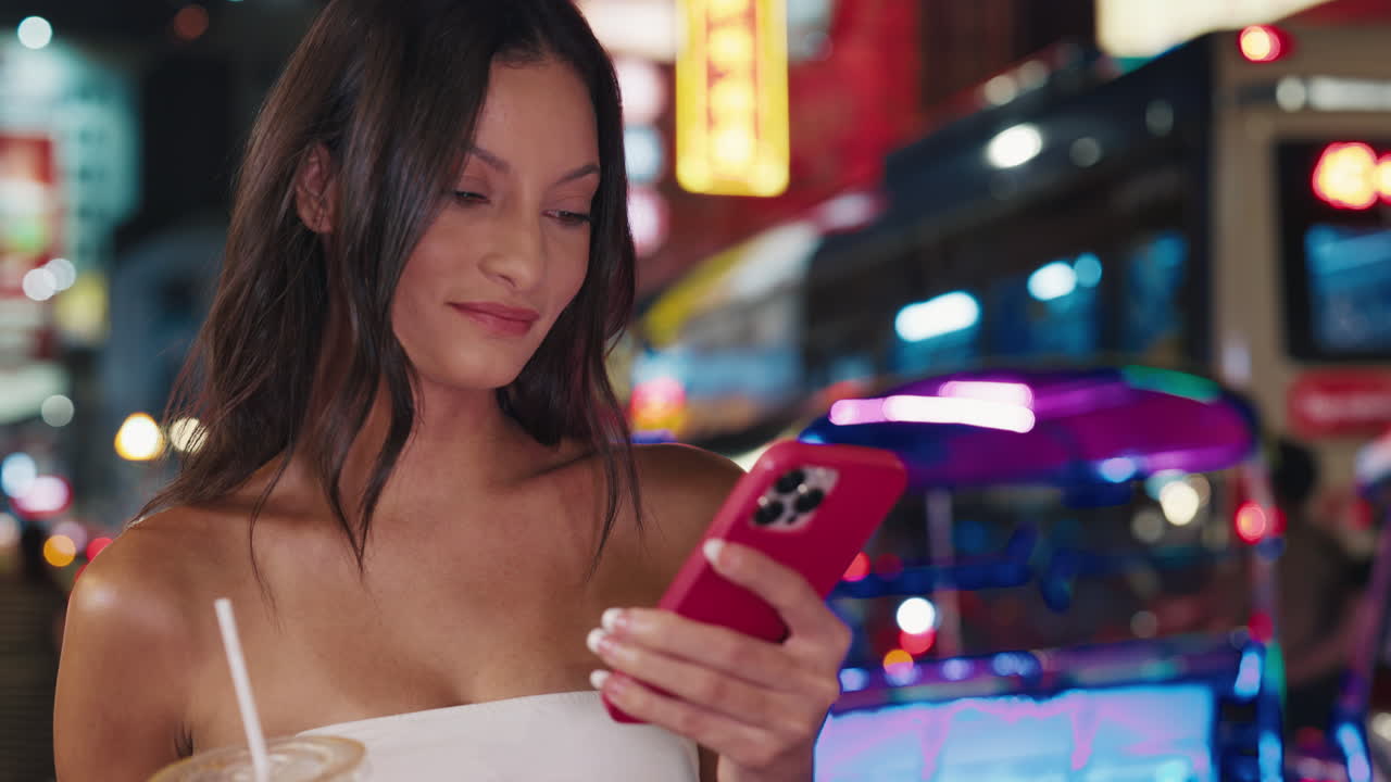Donna che usa il telefono cellulare in un vivace mercato notturno