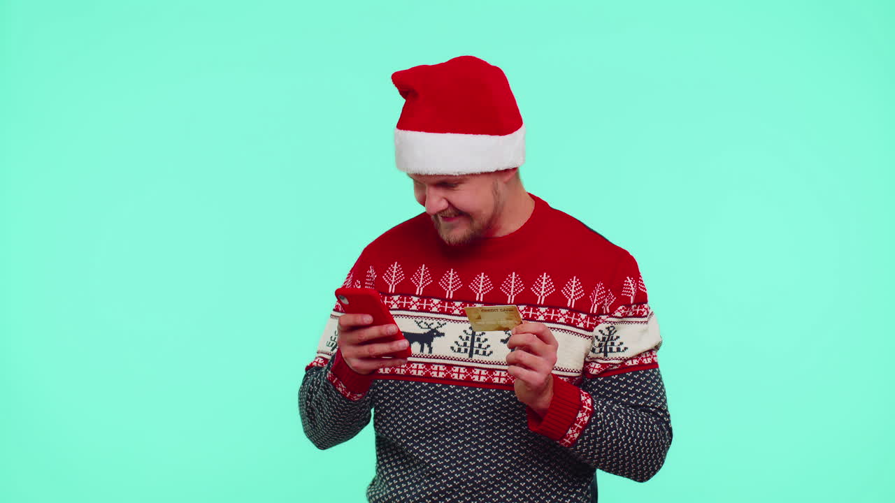 크리스마스 빨간 스웨터에 남자는 휴대전화와 플라스틱 신용 카드를 사용, 승리, 캘리브레이트, 와우