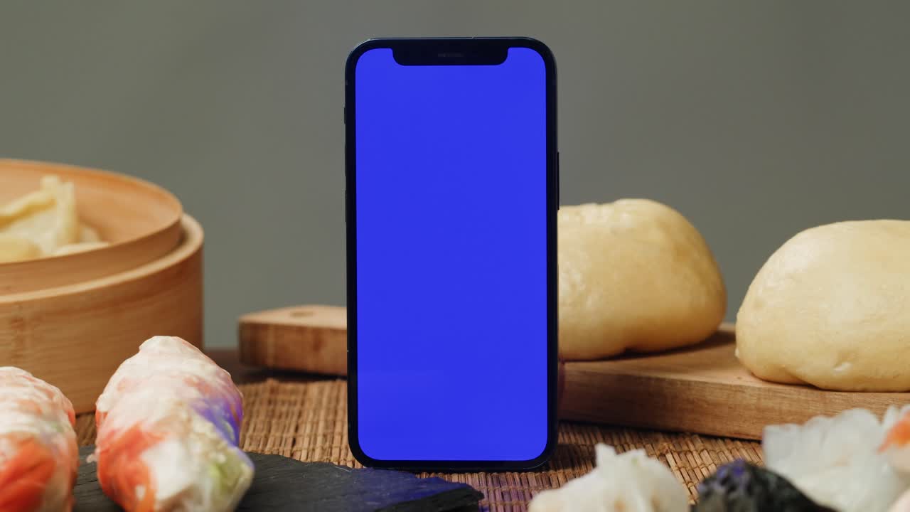 Smartphone with Blue Screen Display Surrounded by Asian Food