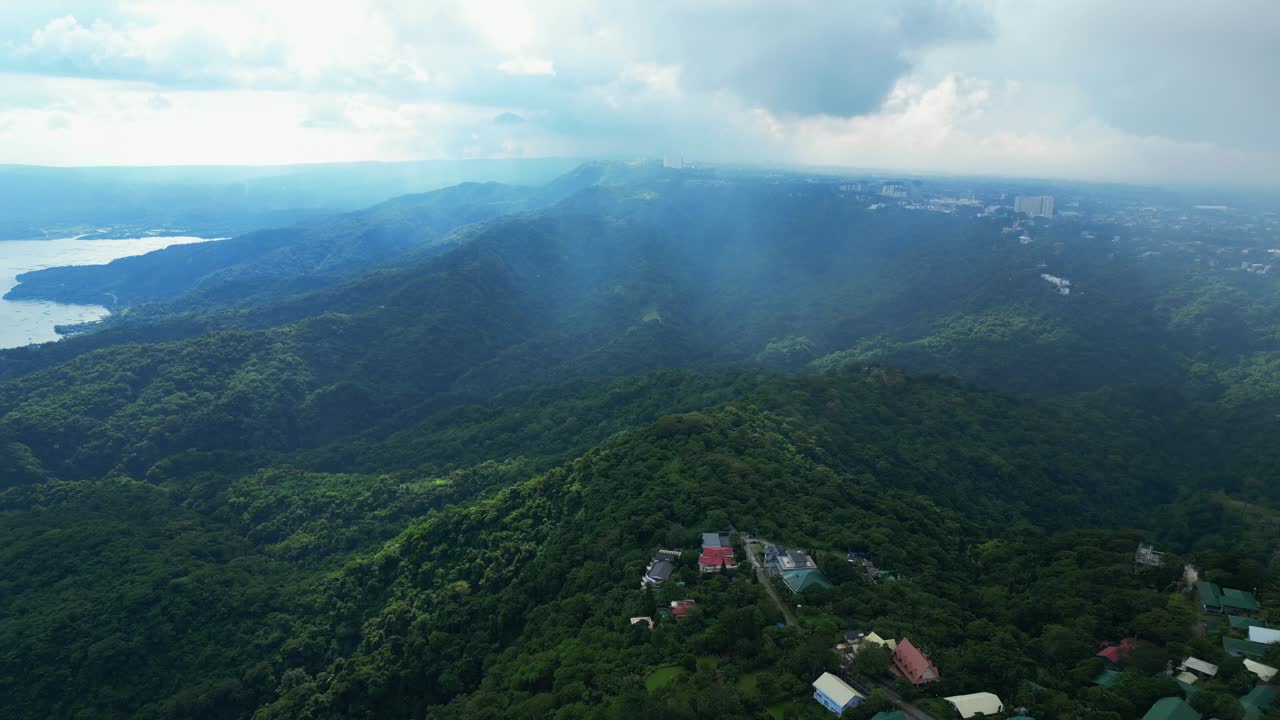 A wide aerial of misty forested hills beneath a cloudy sky in Talisay, Batangas, Philippines