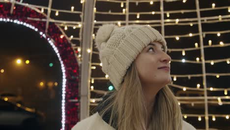 Mujer-Mirando-Adornos-Navideños-En-La-Calle-Por-La-Noche-Y-Sonriendo