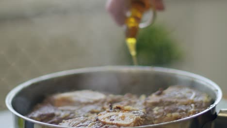 woman pouring oil to pan with veal shank