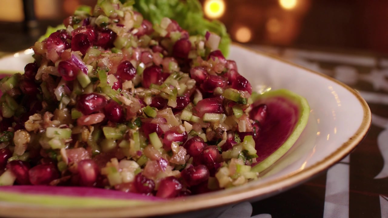 Deliziosa insalata turca di melograno (Gavurdağı salatası) mescolata con un cucchiaio su un elegante piatto da portata