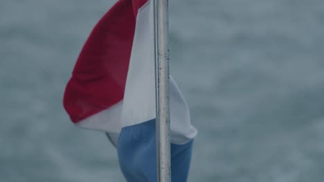 Zeitlupe-Nach-Unten-Kippender-Schuss-Der-Holländischen-Flagge,-Die-Sich-Bei-Windigen-Bedingungen-Kräuselt