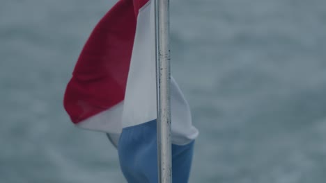 slow-motion downwards tilting shot of the dutch flag rippling in the windy conditions