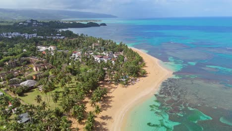 aerial backwards shot of sandy beach las ballenas, samana during sunny day. coral reef in clear caribbean sea. luxury hotel resort with swimming pool. wide shot.