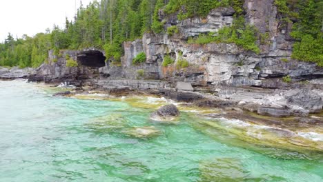 Backward-drone-shot-of-crashing-waves-in-the-coast-of-Georgian-Bay,-Ontario,-Canada