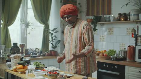 indian chef in turban explaining recipe to camera in kitchen