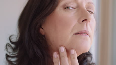 Retrato-De-Mujer-Madura-Aplicando-Maquillaje-Preparándose-En-Casa-Mirándose-En-El-Espejo-Disfrutando-De-Su-Tez-Natural