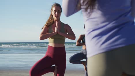 grupo de diversas amigas practicando yoga en la playa