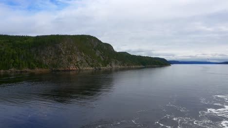view of mountains from the stern of a ship cruising along saguenay fjord outside of la baie, qc, canada