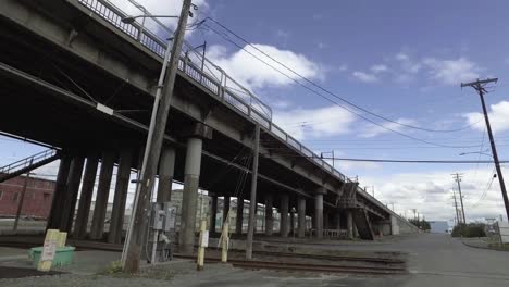 Rolling-view-of-the-11th-St-Bridge-in-the-Port-of-Tacoma,-Washington,-Partly-cloudy,-green-grass,-Concrete-colmns