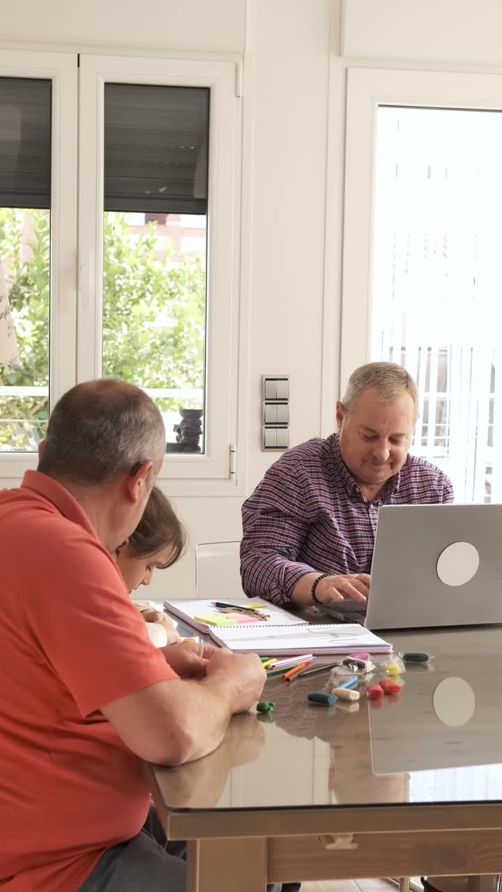 Grandpa playing with a girl while his gay couple working with a laptop