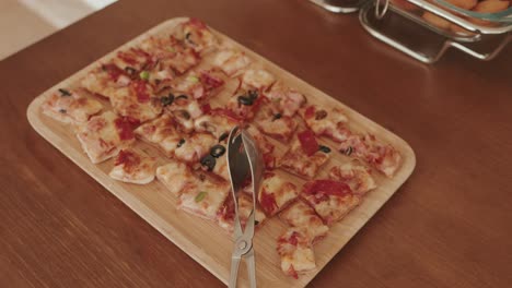 mini square pizza pieces with toppings arranged on wood board ready for self service