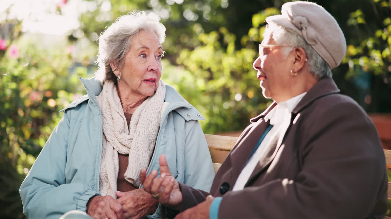 Two elderly women having a conversation on a park bench