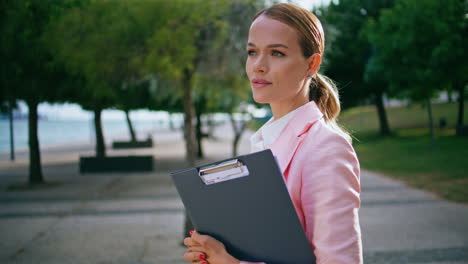 portrait confident businesswoman standing park with folder. calm business lady