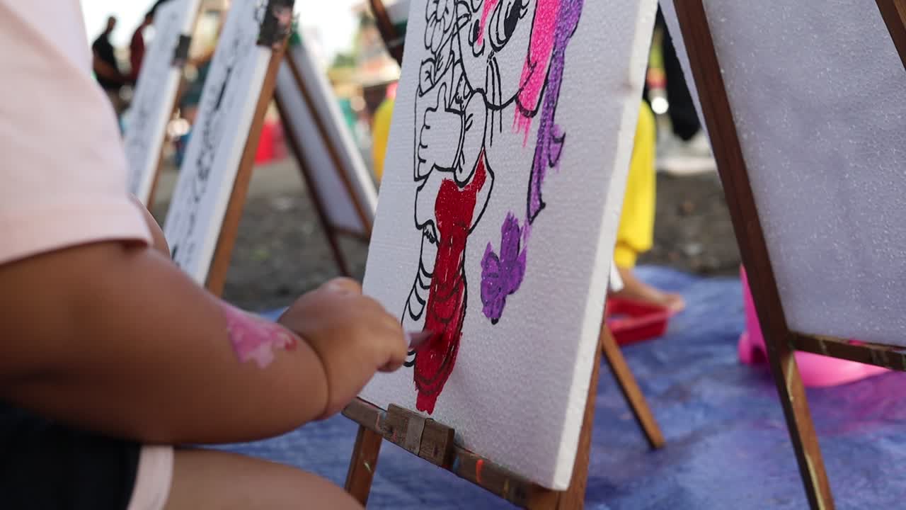 Bambino piccolo che dipinge con un pennello in un'area pubblica.