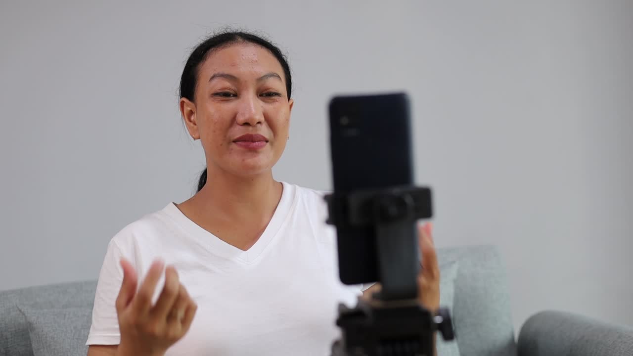 Donna adulta asiatica che parla in diretta video tramite la fotocamera selfie del telefono su un'app di assistenza per la salute mentale. Vlogger asiatica che riprende e condivide contenuti digitali e virtuali online.