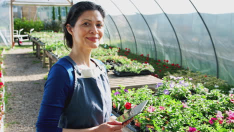 Retrato-De-Una-Mujer-Madura-Propietaria-De-Un-Centro-De-Jardinería-Sosteniendo-Una-Tableta-Digital-En-Invernadero