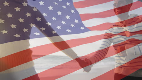 animation of flag of united states of america over biracial couple holding hands by seaside