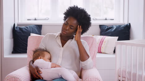 anxious new mother suffering with post natal depression holding sleeping baby girl in nursery at home