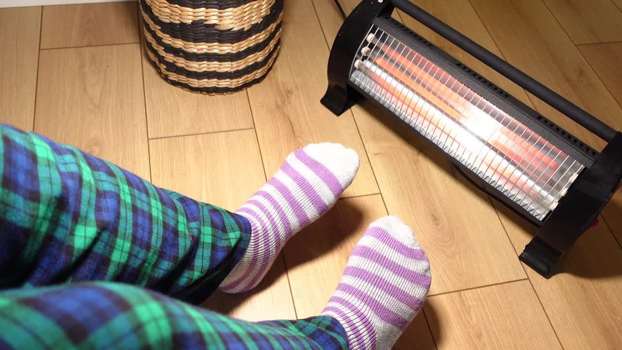A cozy scene with a heater, socks, and a basket on parquet flooring