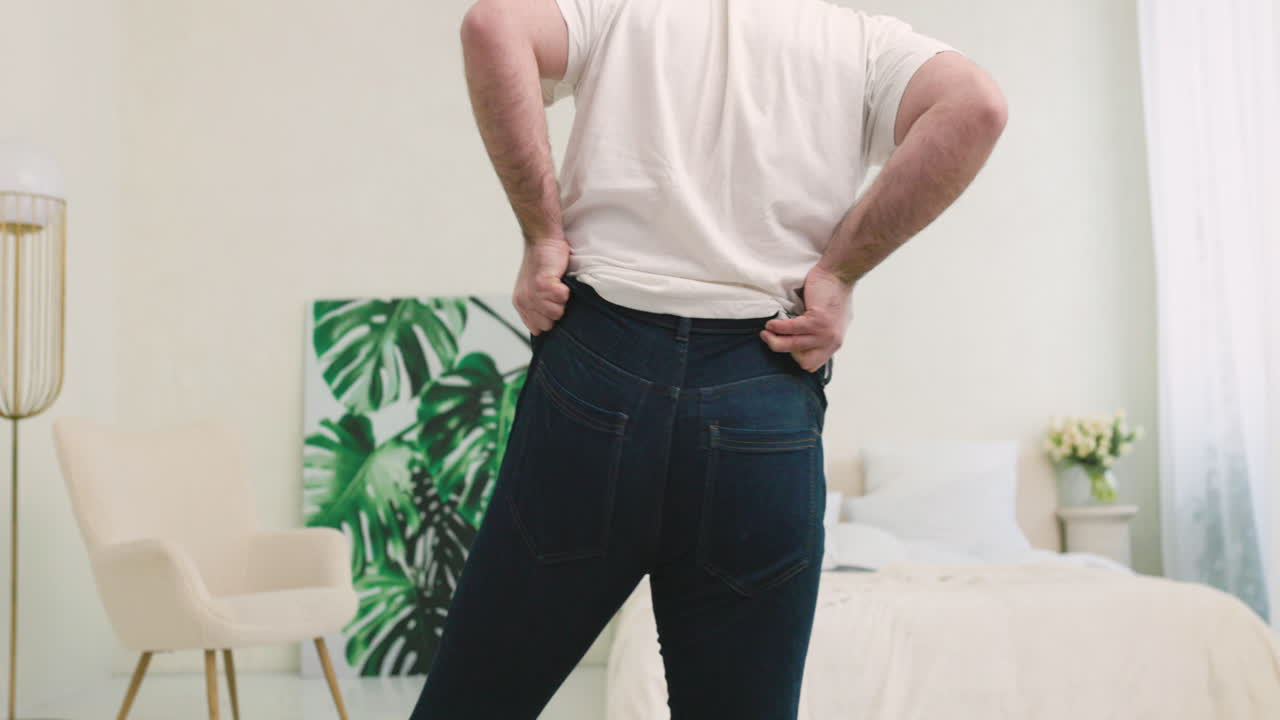 Free stock video - Rear view of man buttoning tight jeans with ...